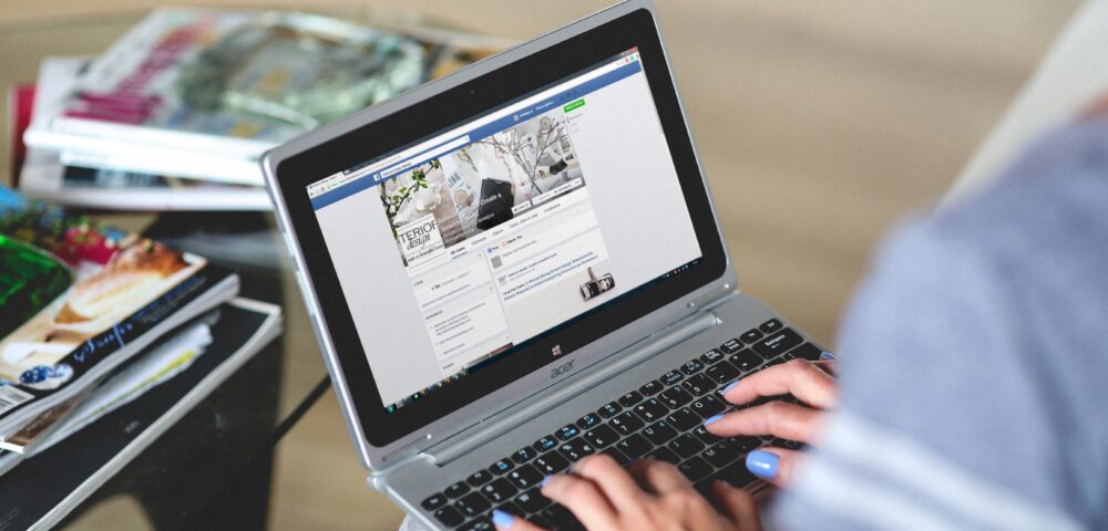 laptop auf knien, facebook seite offen